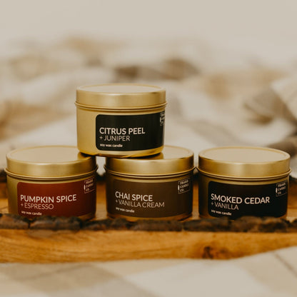 soy wax candles in gold 4 oz tins stacked on a wooden tray