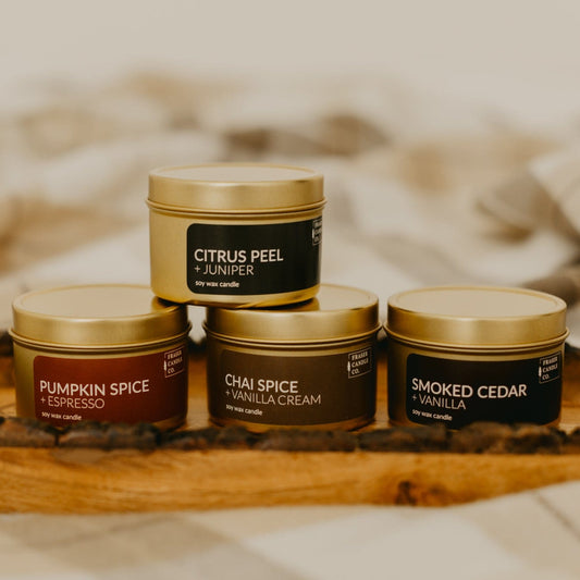 soy wax candles in gold 4 oz tins stacked on a wooden tray