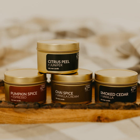 soy wax candles in gold 4 oz tins stacked on a wooden tray